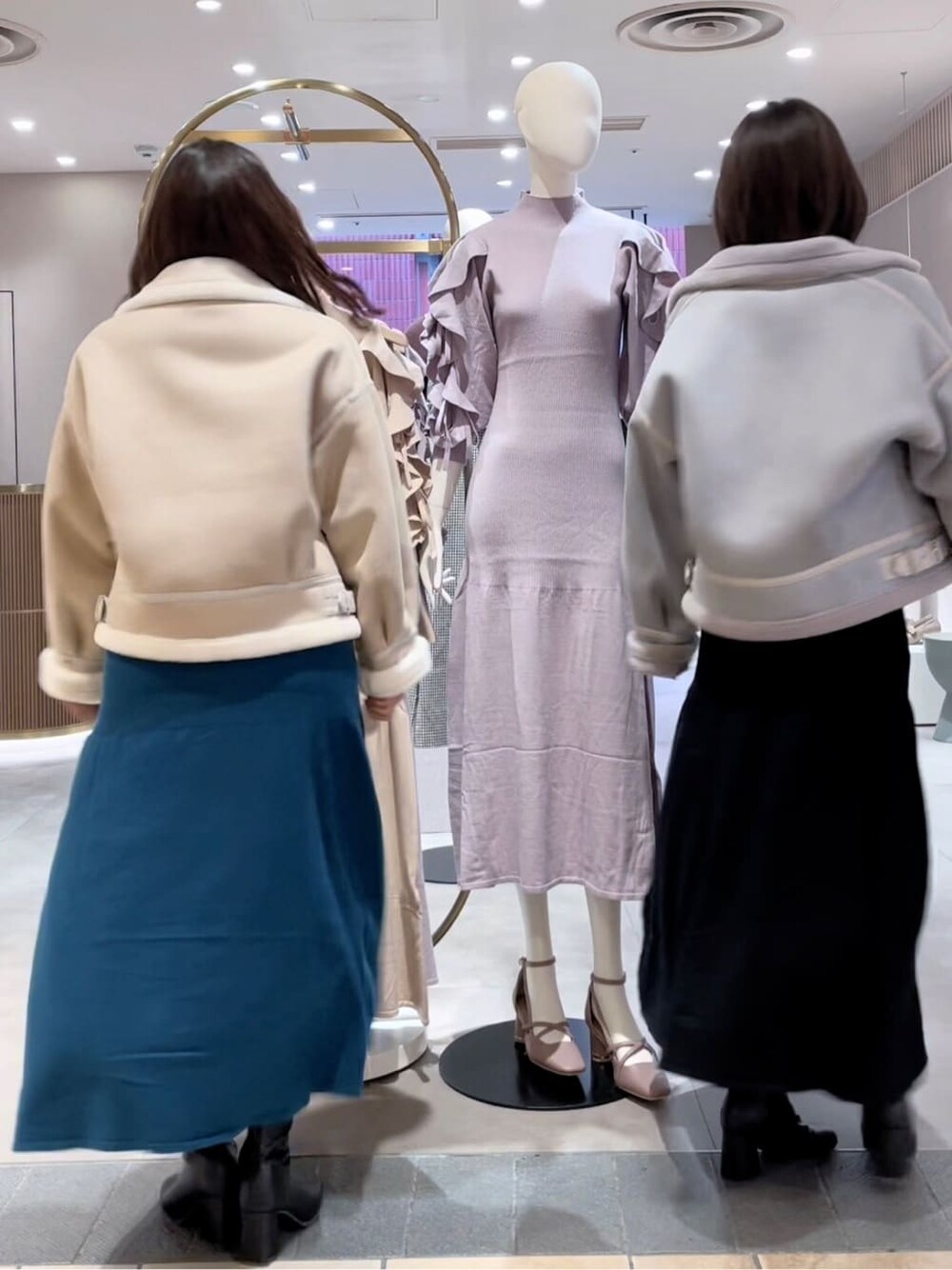 グリーン系のワンピース、ブラック系のブーツ、ホワイト系のブルゾンを着用したレディースの秋コーディネートの2枚目の写真