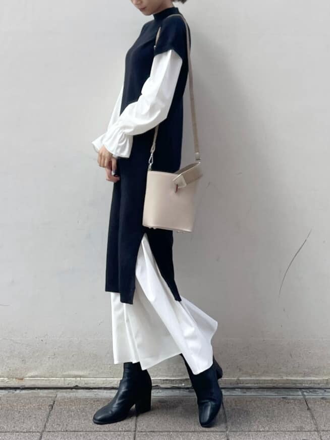 ブラック系のブーツ、ブラック系のワンピース、ベージュ系のハンドバッグを着用したレディースの秋コーディネートの3枚目の写真