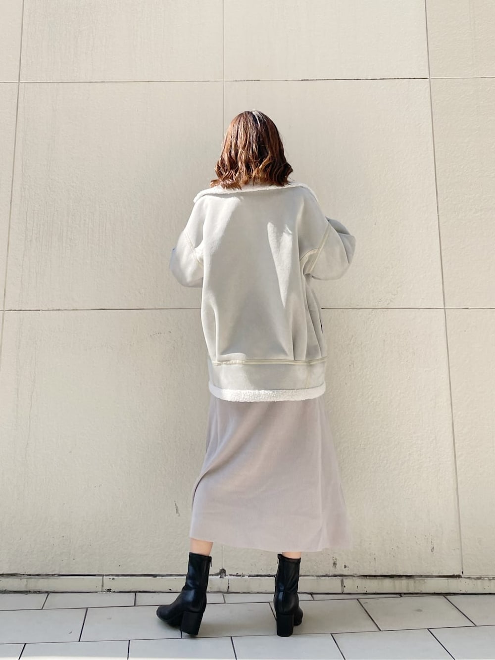 グレー系のブルゾン、ブラック系のブーツ、グレー系のワンピースを着用したレディースの秋コーディネートの2枚目の写真