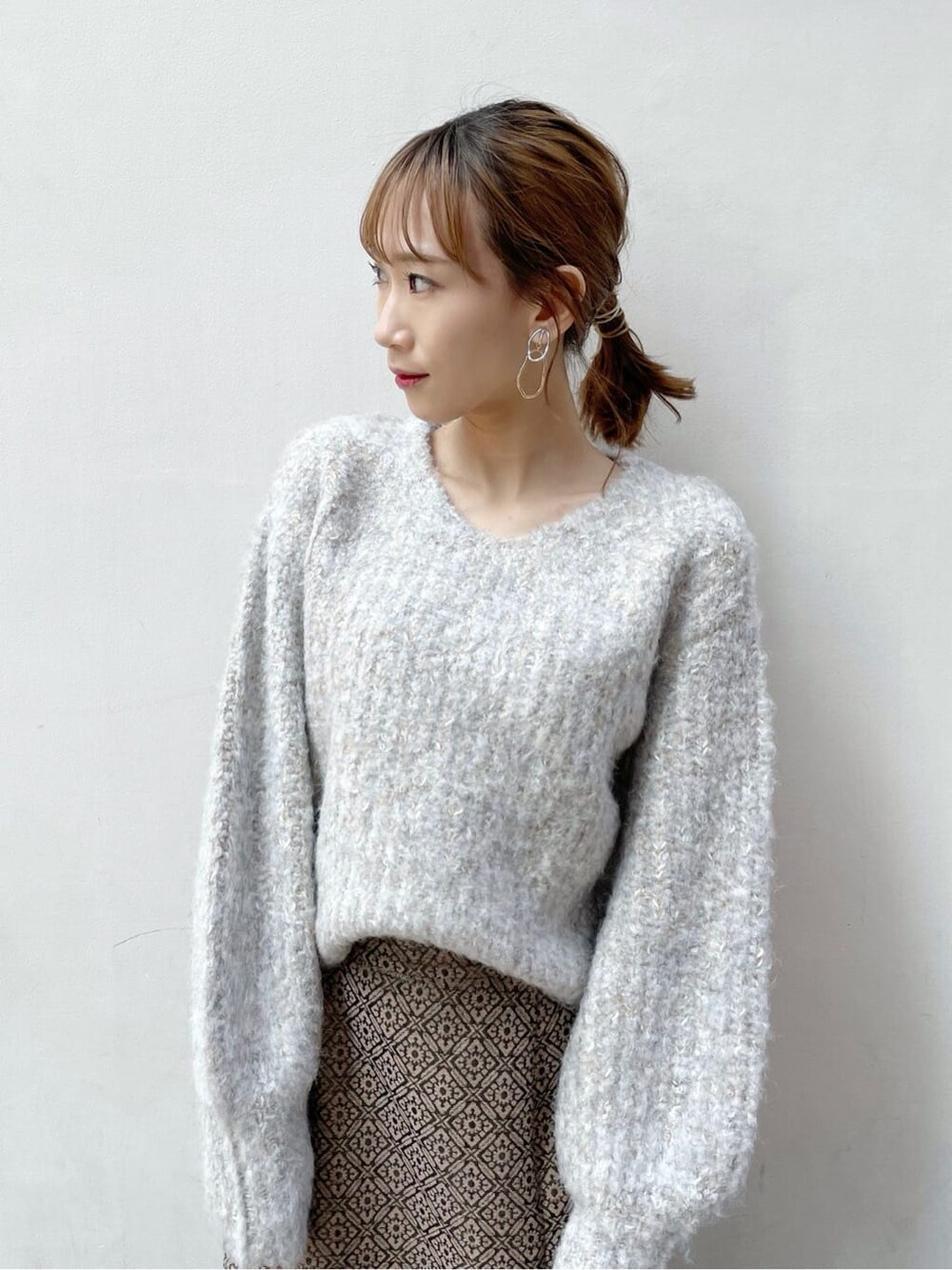 ブラック系のブーツ、ベージュ系のニット/セーター、ゴールド系のスカートを着用したレディースの秋コーディネートの4枚目の写真