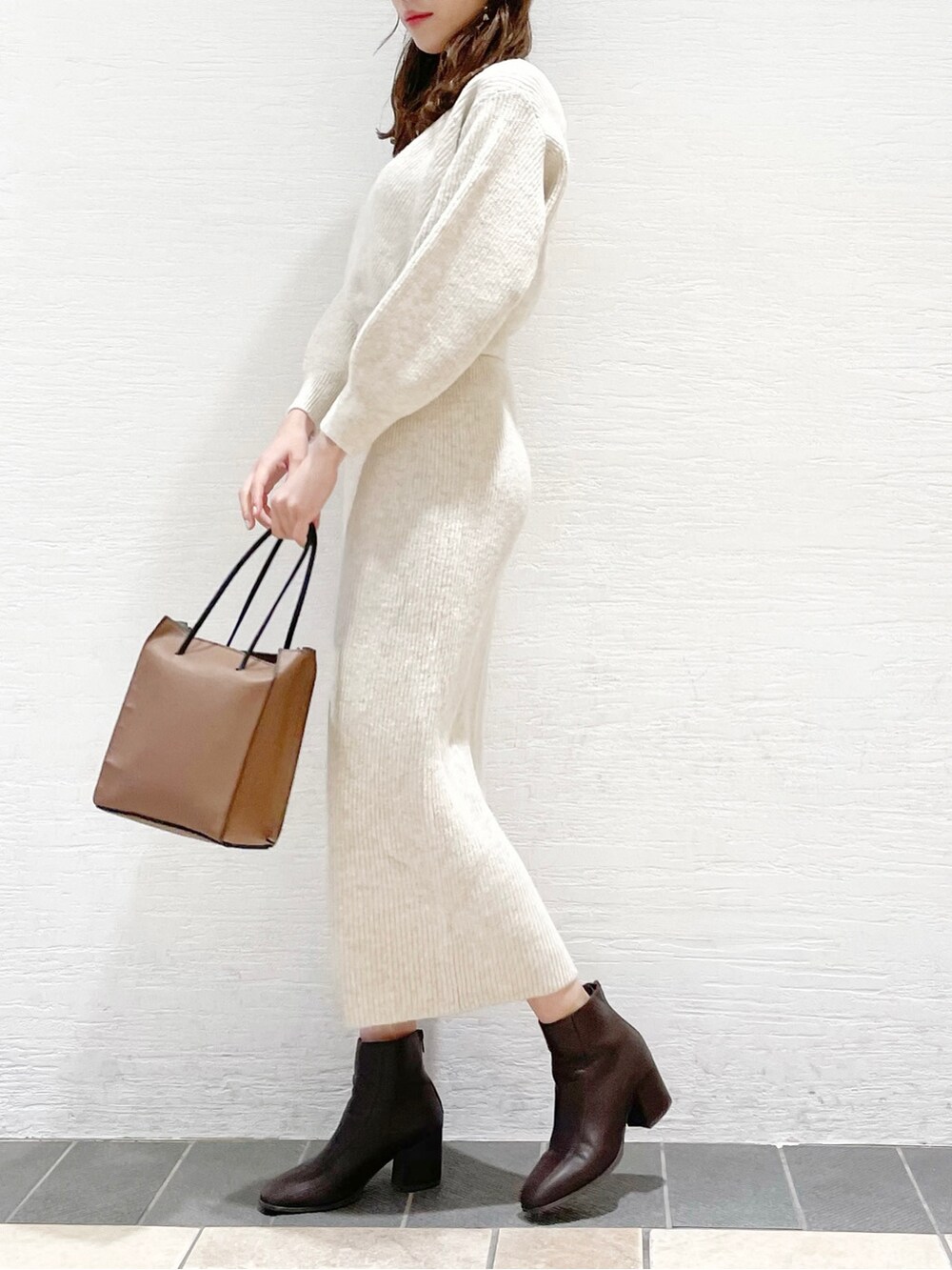ブラウン系のブーツ、ブラウン系のハンドバッグ、ベージュ系のワンピースを着用したレディースの冬コーディネートの2枚目の写真