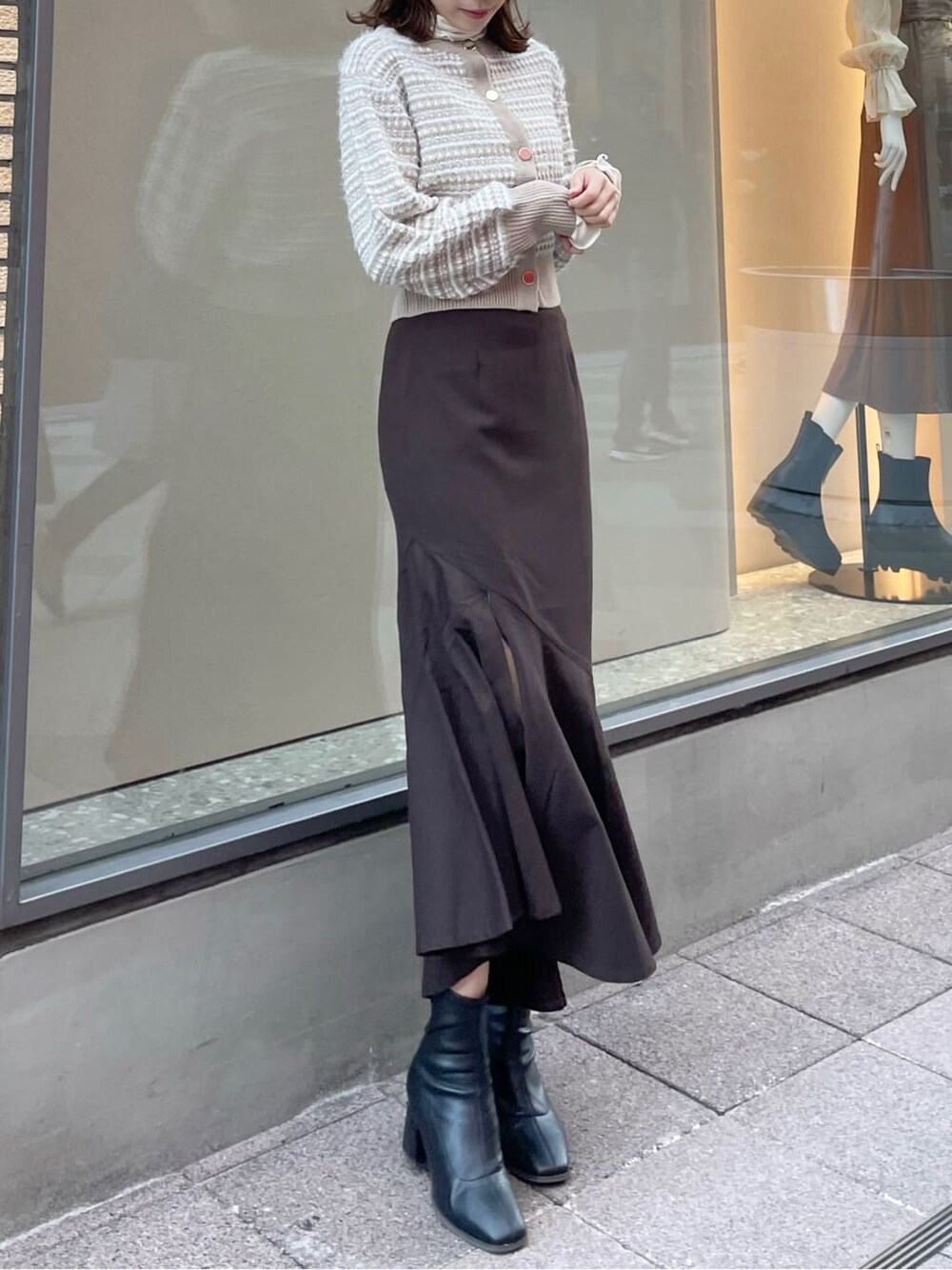 ブラウン系のスカート、ブラック系のブーツ、ベージュ系のカーディガン/ボレロを着用したレディースの秋コーディネートの4枚目の写真