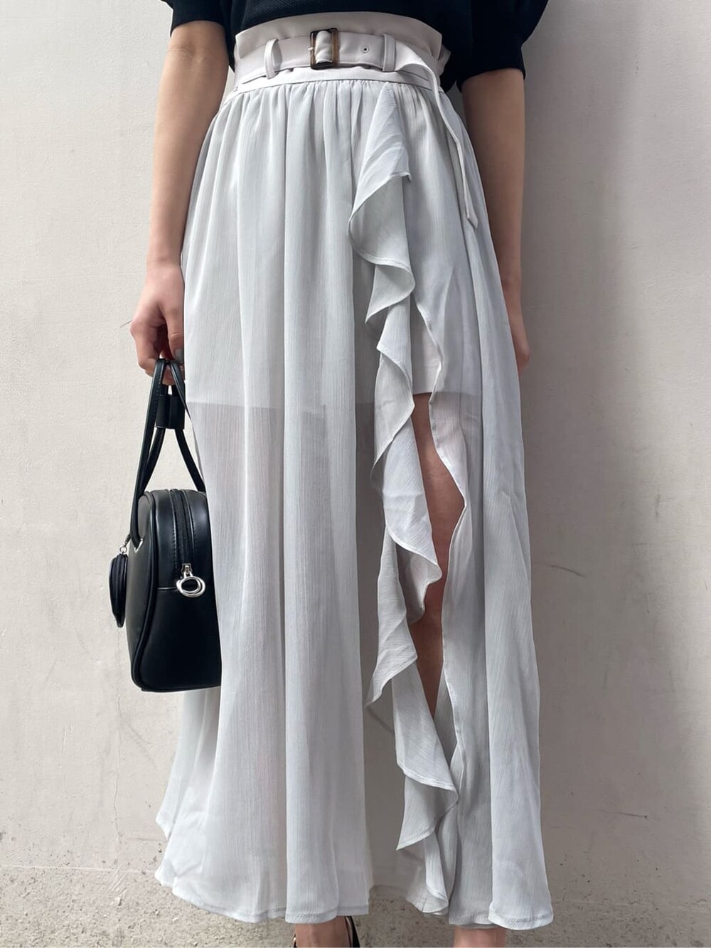 グレー系のスカート、ブラック系のサンダル、ホワイト系のニット/セーターを着用したレディースの春コーディネートの8枚目の写真