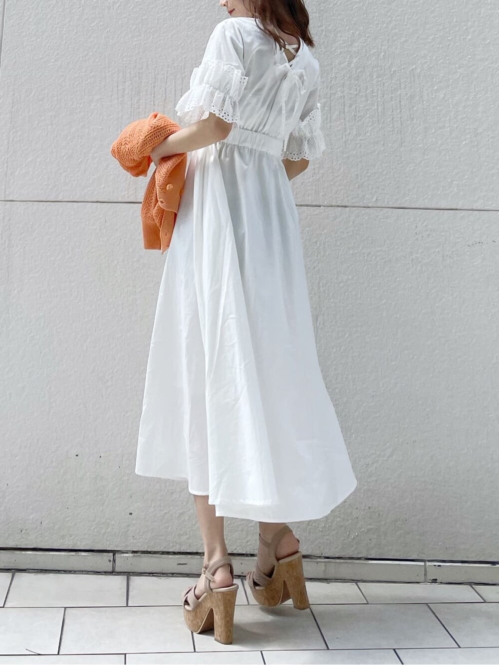 ホワイト系のワンピース、ベージュ系のサンダル、オレンジ系のカーディガン/ボレロを着用したレディースの春コーディネートの5枚目の写真