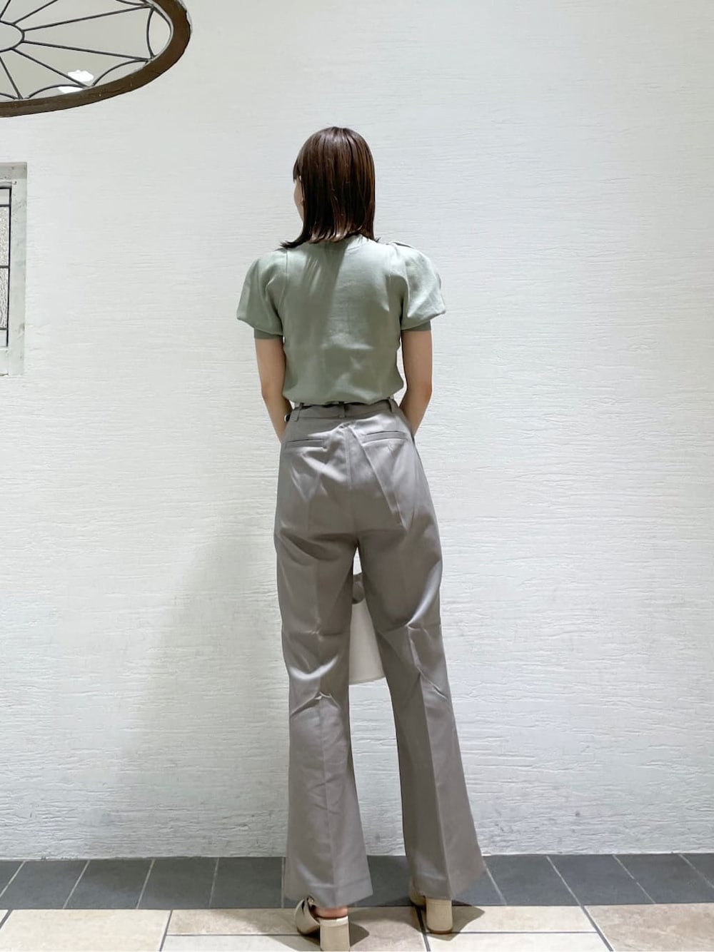 グレー系のその他パンツ、ホワイト系のハンドバッグ、グリーン系のニット/セーターを着用したレディースの夏コーディネートの3枚目の写真