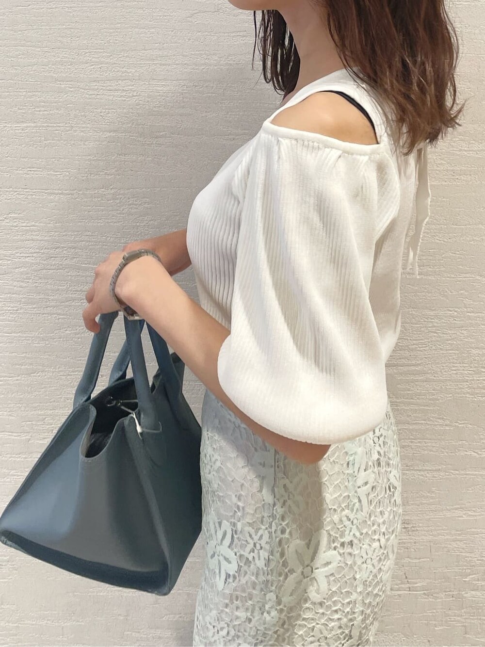 ホワイト系のニット/セーター、ブルー系のスカート、ブルー系のハンドバッグを着用したレディースの春コーディネートの6枚目の写真