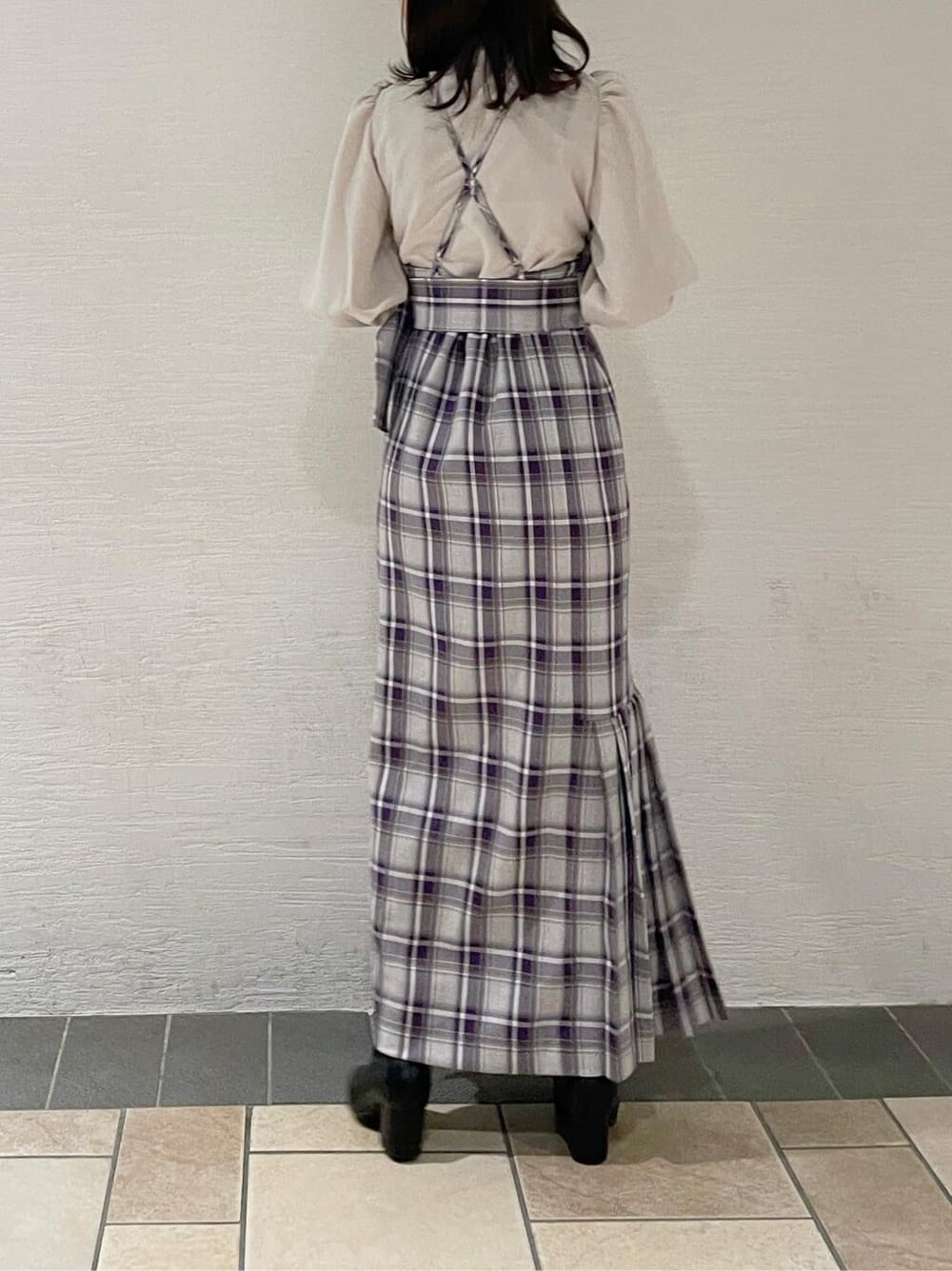 ブラック系のブーツ、ホワイト系のチェスターコート、パープル系のジャンパースカートを着用したレディースの冬コーディネートの5枚目の写真