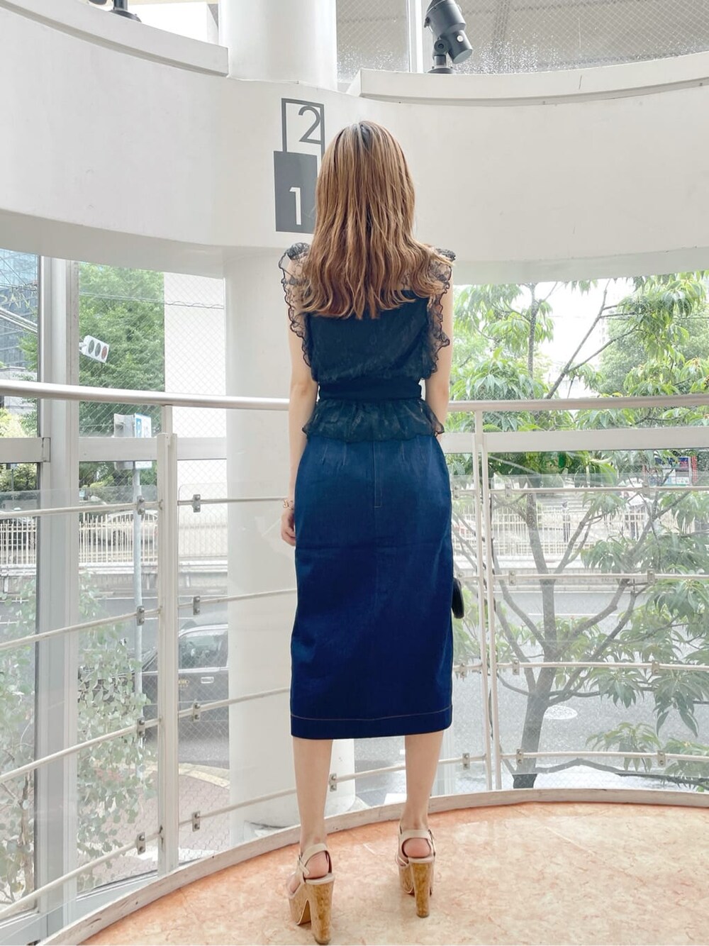 ブラック系のハンドバッグ、ブラック系のシャツ/ブラウス、ブルー系のスカートを着用したレディースの夏コーディネートの2枚目の写真