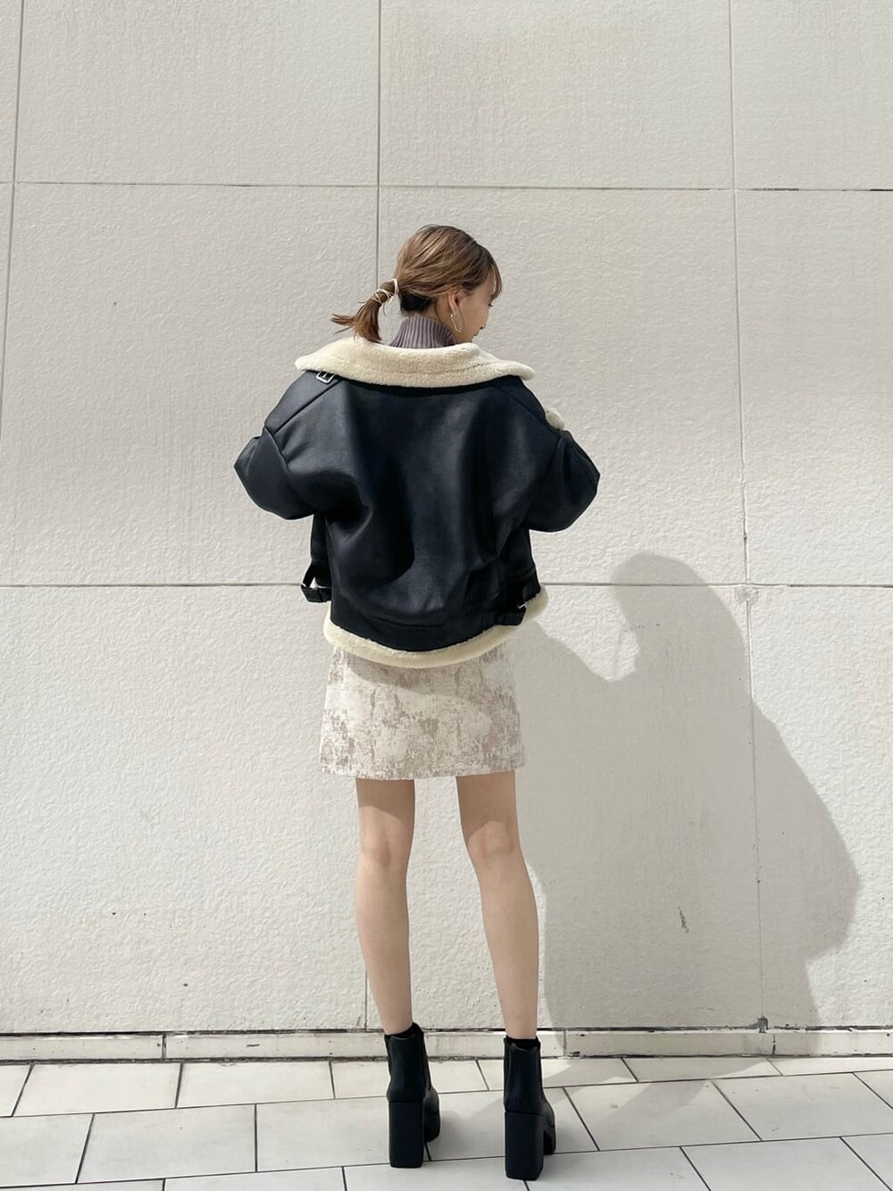 ブラック系のブルゾン、ベージュ系のスカート、ブラック系のブーツを着用したレディースの秋コーディネートの2枚目の写真