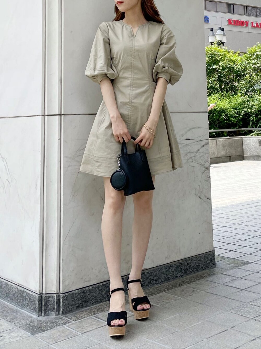 ブラック系のサンダル、ブラック系のハンドバッグ、ベージュ系のワンピースを着用したレディースの夏コーディネートの3枚目の写真