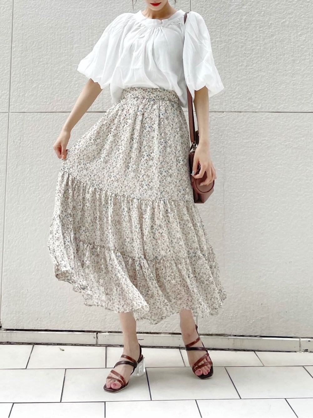 ブラウン系のハンドバッグ、ブラウン系のサンダル、ホワイト系のシャツ/ブラウスを着用したレディースの夏コーディネートの3枚目の写真