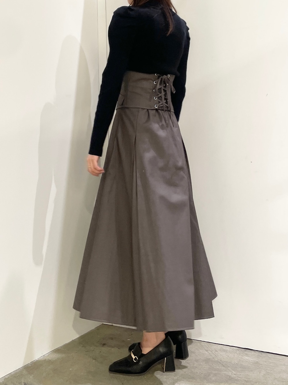 ブラック系のニット/セーター、ブラック系のローファー、グレー系のスカートを着用したレディースの秋コーディネートの2枚目の写真