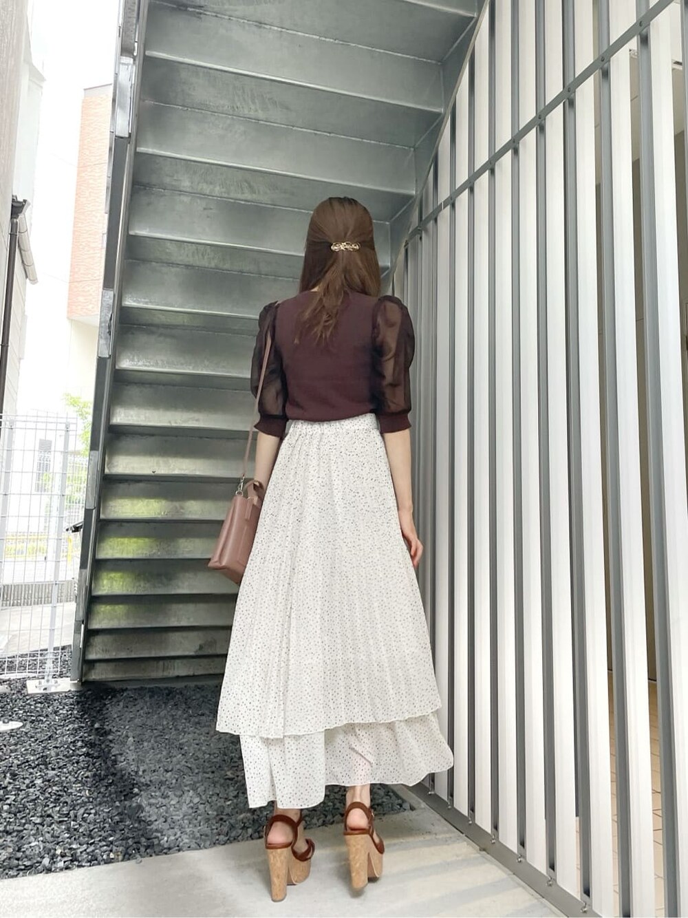 ブラウン系のサンダル、ブラウン系のハンドバッグ、ホワイト系のスカートを着用したレディースの夏コーディネートの3枚目の写真
