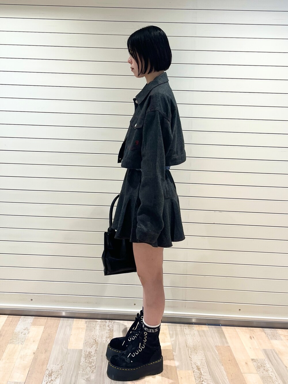 グレー系のワンピース、ブルー系のニット/セーター、ブラック系のハンドバッグを着用したレディースの秋コーディネートの3枚目の写真