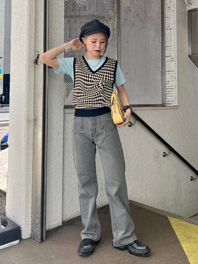 ブラック系のデニムパンツ、ブラック系のニット/セーター、イエロー系のボストンバッグを着用したレディースの夏コーディネートの2枚目の写真