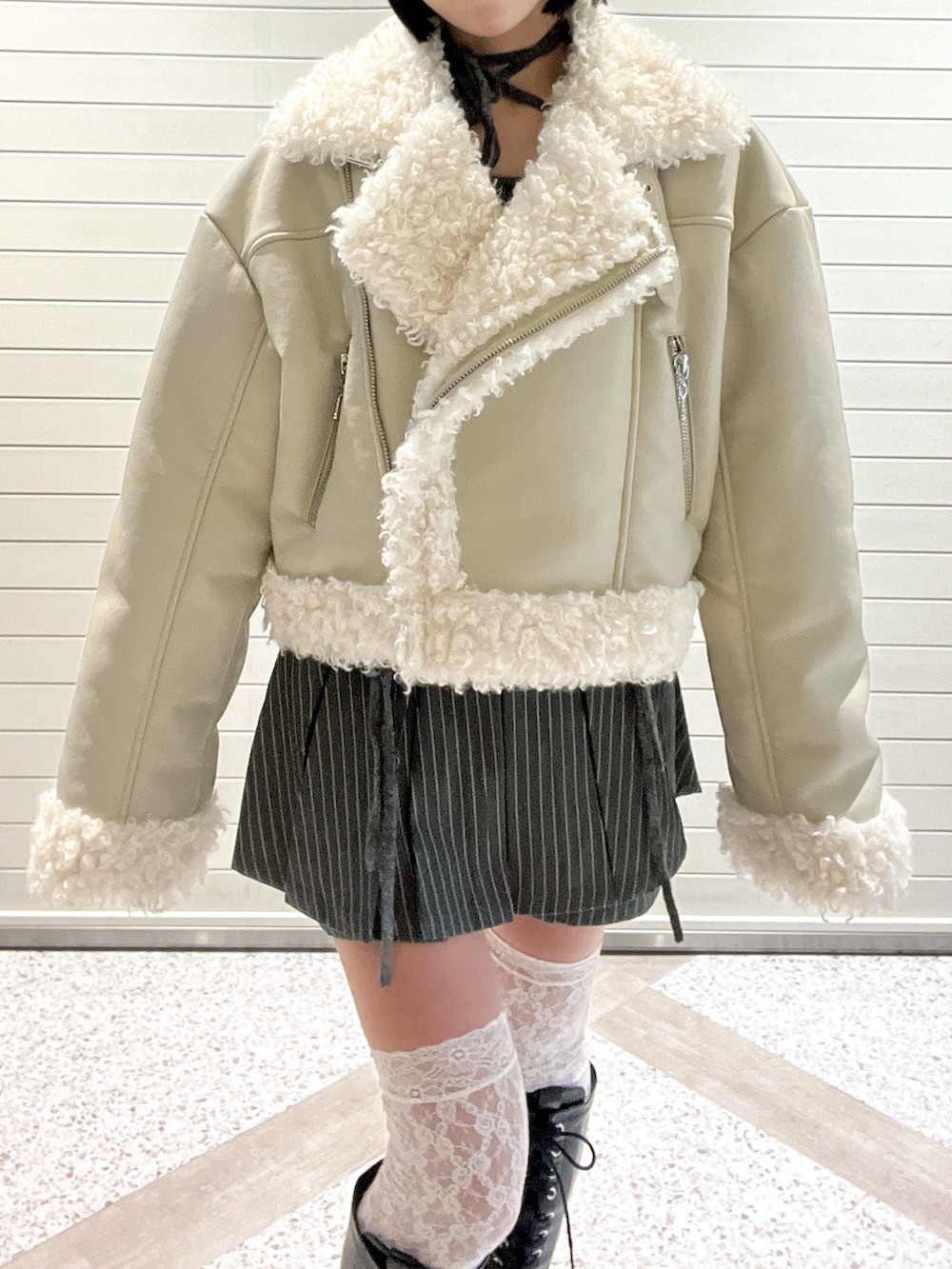 ホワイト系のムートンコート、グレー系のスカート、ブラック系のブーツを着用したレディースの冬コーディネートの6枚目の写真