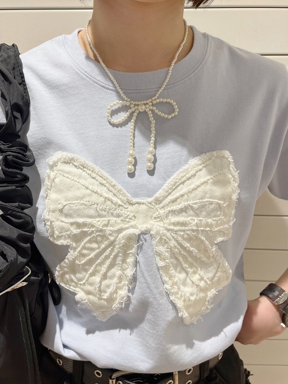 ブラック系のショルダーバッグ、ブラック系のスカート、ブルー系のTシャツ/カットソーを着用したレディースの春コーディネートの6枚目の写真