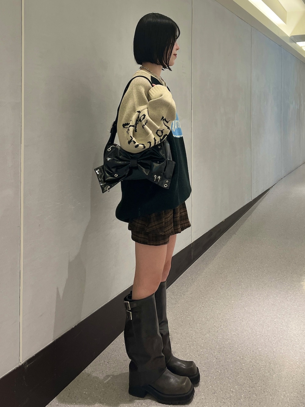 ブラック系のニット/セーター、ブラウン系のスカート、ブラック系のショルダーバッグを着用したレディースの秋コーディネートの4枚目の写真