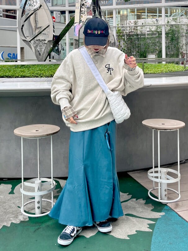 グレー系のスウェット、ベージュ系のシャツ/ブラウス、ブルー系のスカートを着用したレディースの秋コーディネートの2枚目の写真