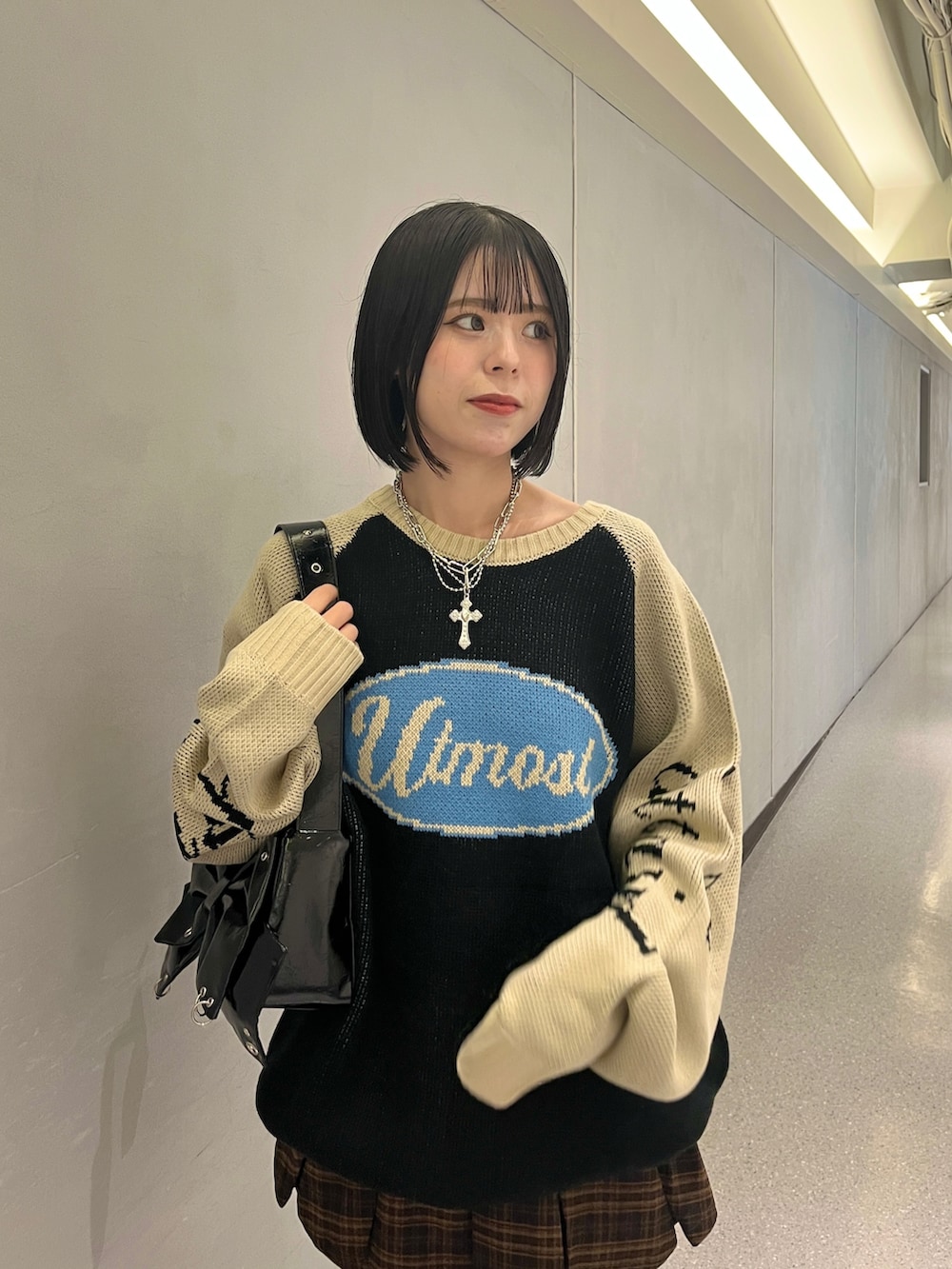 ブラック系のニット/セーター、ブラウン系のスカート、ブラック系のショルダーバッグを着用したレディースの秋コーディネートの6枚目の写真