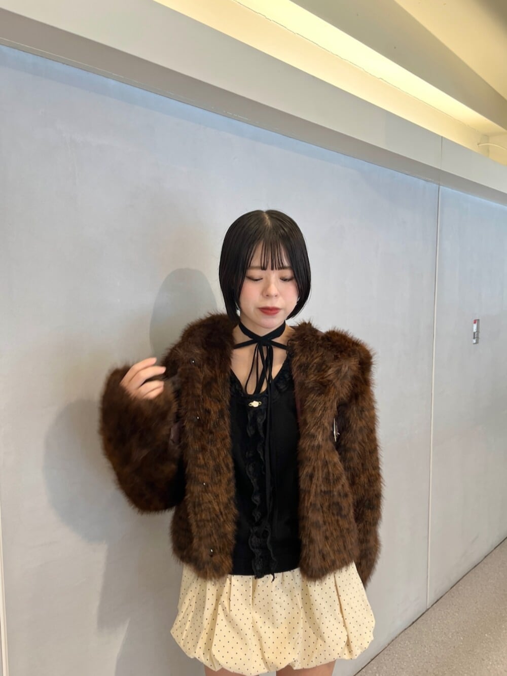 ホワイト系のスカート、ブラウン系のブルゾン、ブラック系のニット/セーターを着用したレディースの秋コーディネートの5枚目の写真