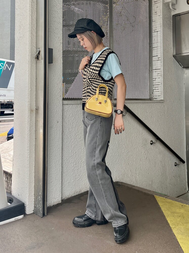 ブラック系のデニムパンツ、ブラック系のニット/セーター、イエロー系のボストンバッグを着用したレディースの夏コーディネートの3枚目の写真