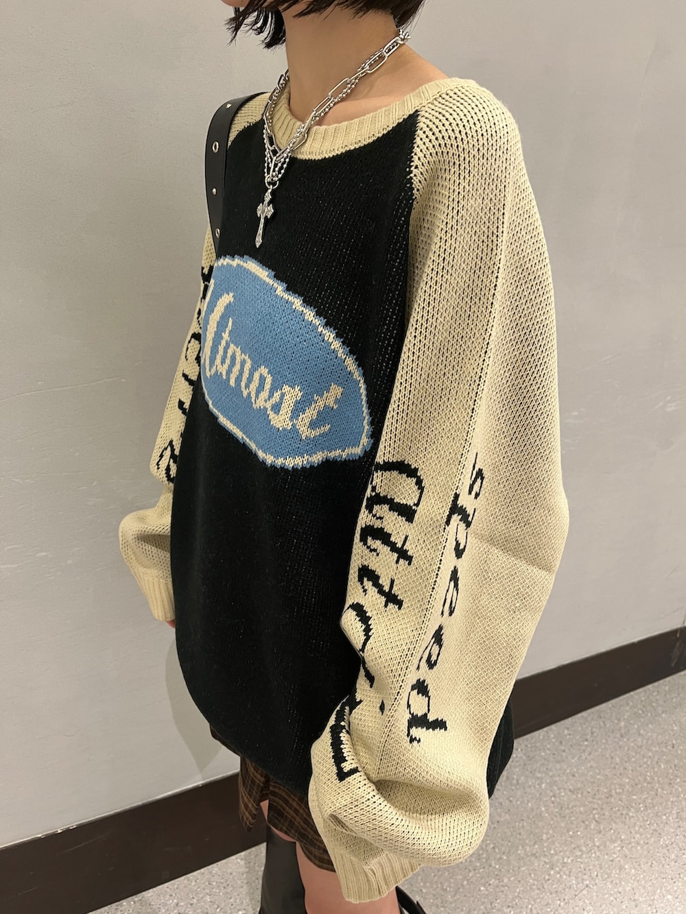 ブラック系のニット/セーター、ブラウン系のスカート、ブラック系のショルダーバッグを着用したレディースの秋コーディネートの8枚目の写真