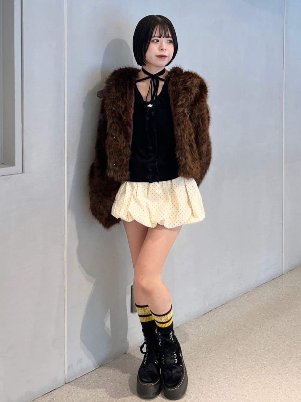 ホワイト系のスカート、ブラウン系のブルゾン、ブラック系のニット/セーターを着用したレディースの秋コーディネートの2枚目の写真