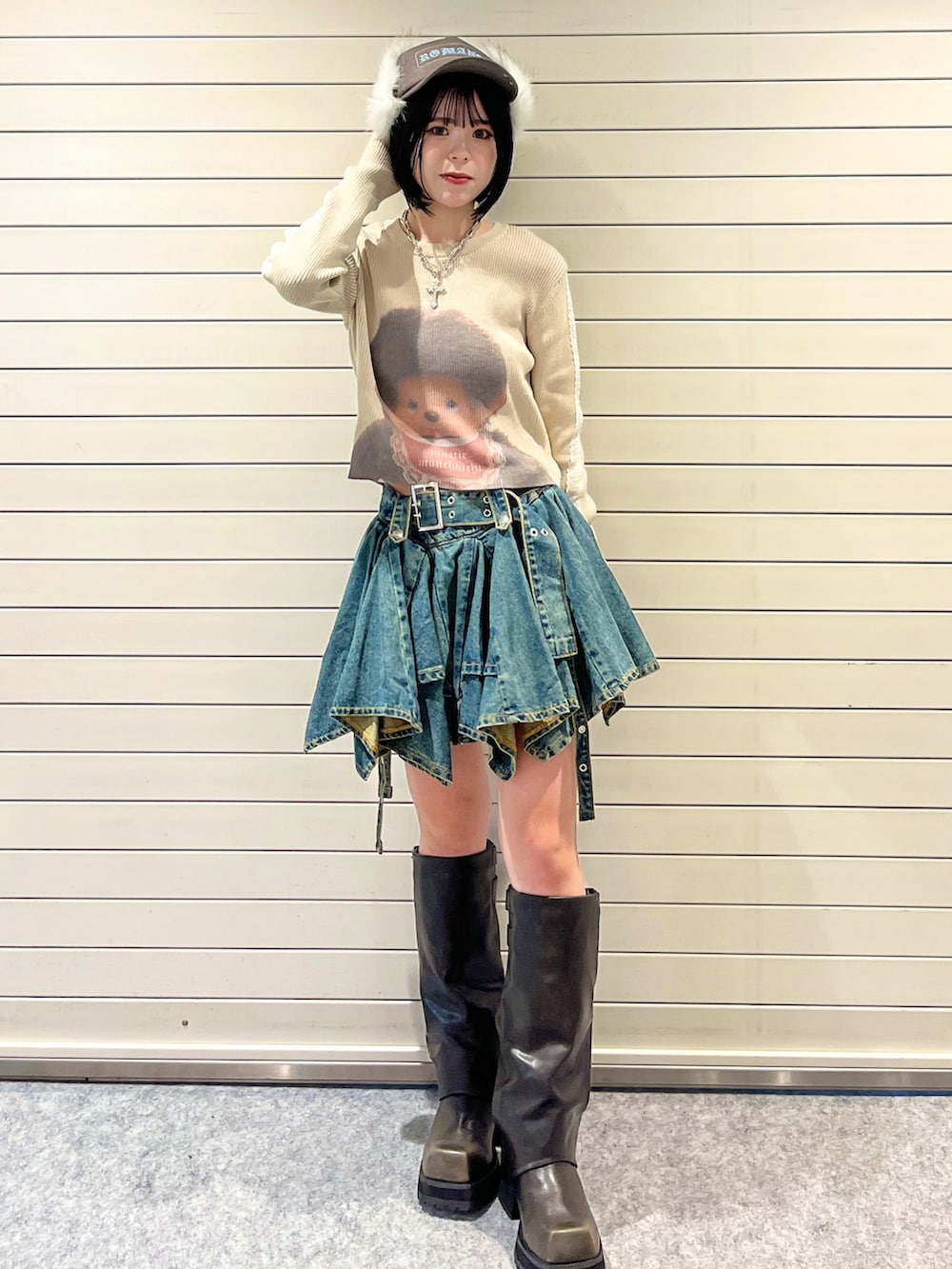 ホワイト系のニット/セーター、ブルー系のデニムスカート、ブラウン系のキャップを着用したレディースの秋コーディネートの2枚目の写真