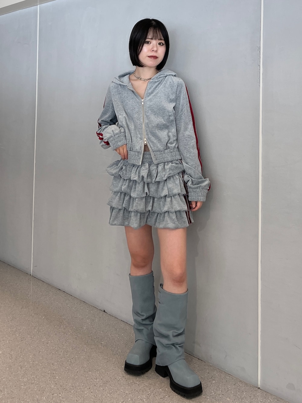 グレー系のパーカー、グレー系のスカート、ブルー系のブーツを着用したレディースの夏コーディネートの2枚目の写真