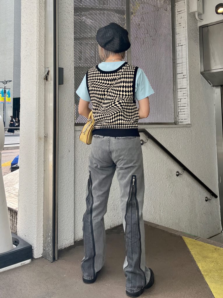 ブラック系のデニムパンツ、ブラック系のニット/セーター、イエロー系のボストンバッグを着用したレディースの夏コーディネートの4枚目の写真