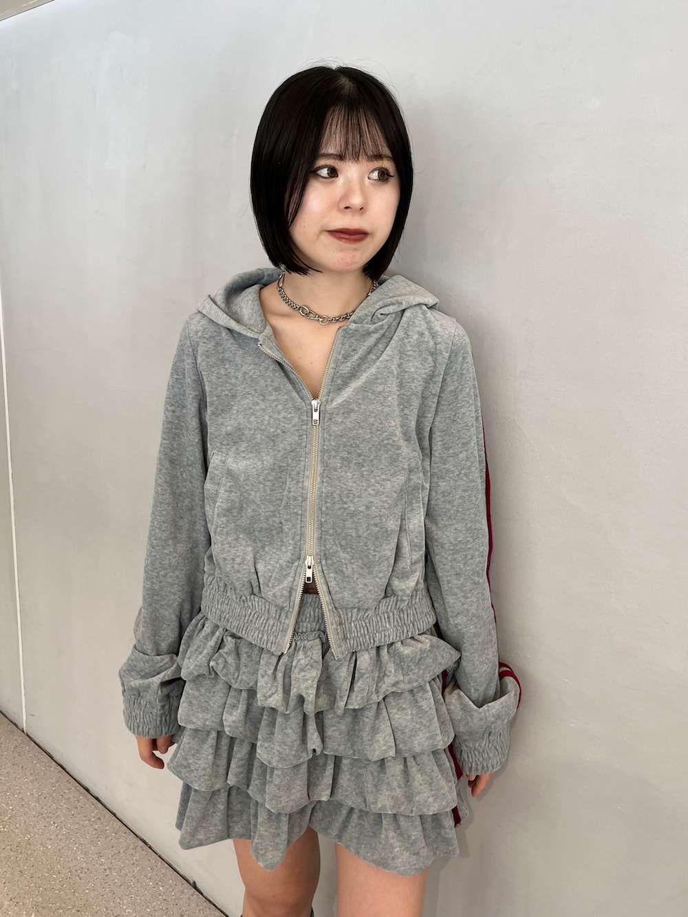 グレー系のパーカー、グレー系のスカート、ブルー系のブーツを着用したレディースの夏コーディネートの6枚目の写真