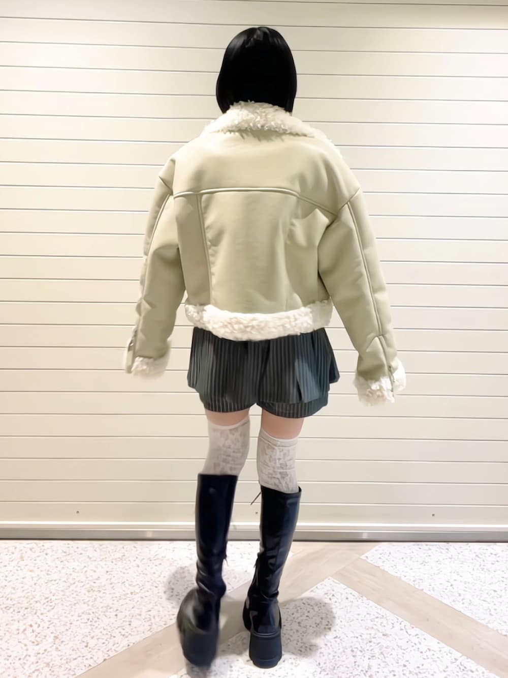 ホワイト系のムートンコート、グレー系のスカート、ブラック系のブーツを着用したレディースの冬コーディネートの4枚目の写真