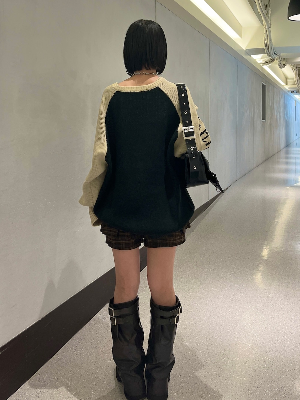 ブラック系のニット/セーター、ブラウン系のスカート、ブラック系のショルダーバッグを着用したレディースの秋コーディネートの5枚目の写真