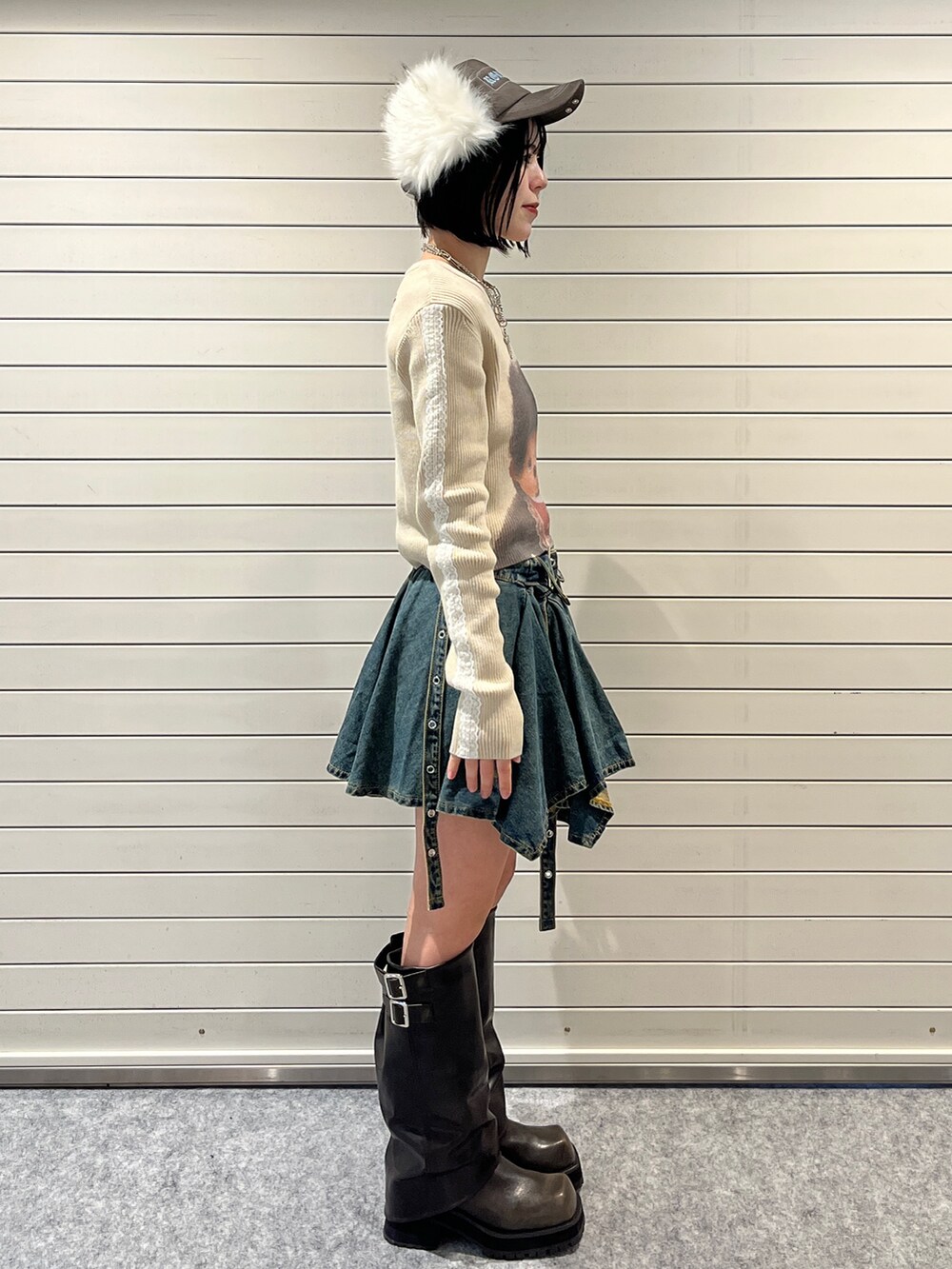 ホワイト系のニット/セーター、ブルー系のデニムスカート、ブラウン系のキャップを着用したレディースの秋コーディネートの3枚目の写真