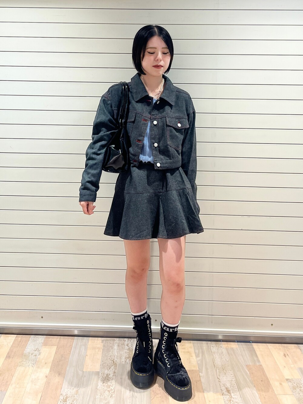 グレー系のワンピース、ブルー系のニット/セーター、ブラック系のハンドバッグを着用したレディースの秋コーディネートの2枚目の写真