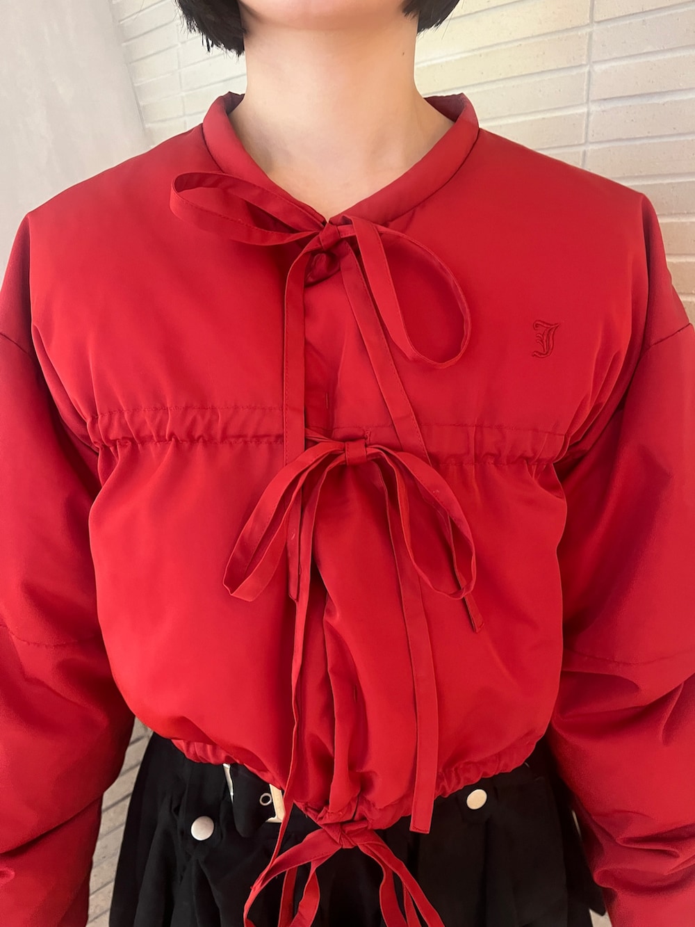 レッド系のブルゾン、ブラック系のスカートを着用したレディースの冬コーディネートの6枚目の写真