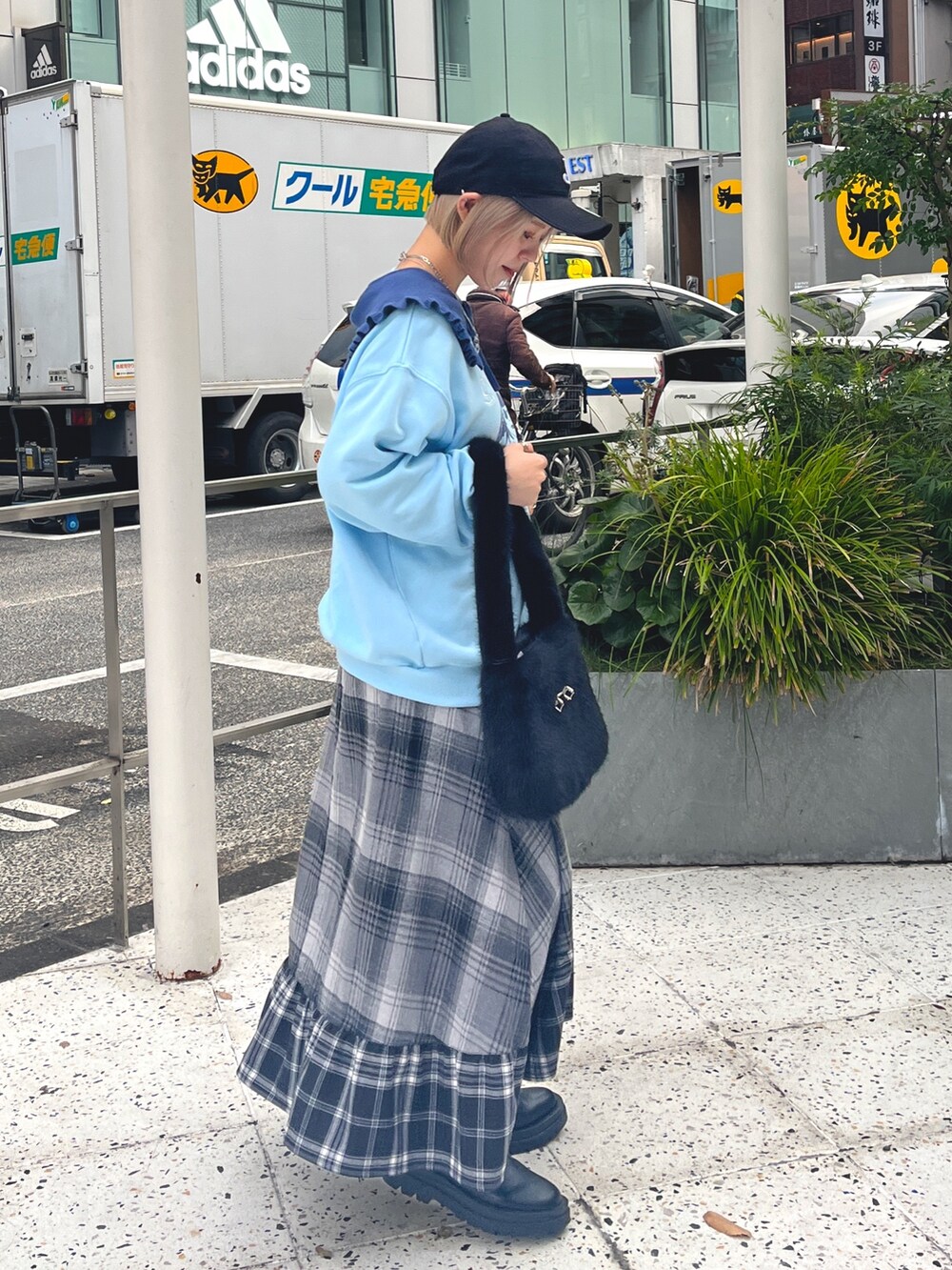 ブラック系のハンドバッグ、ブルー系のニット/セーター、グレー系のスカートを着用したレディースの冬コーディネートの3枚目の写真