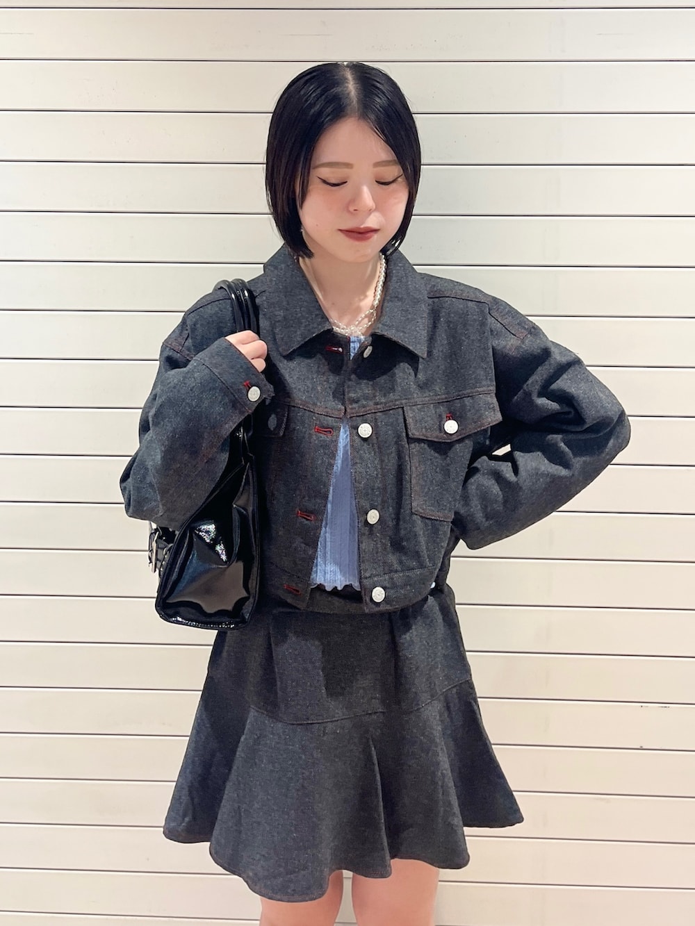 グレー系のワンピース、ブルー系のニット/セーター、ブラック系のハンドバッグを着用したレディースの秋コーディネートの5枚目の写真