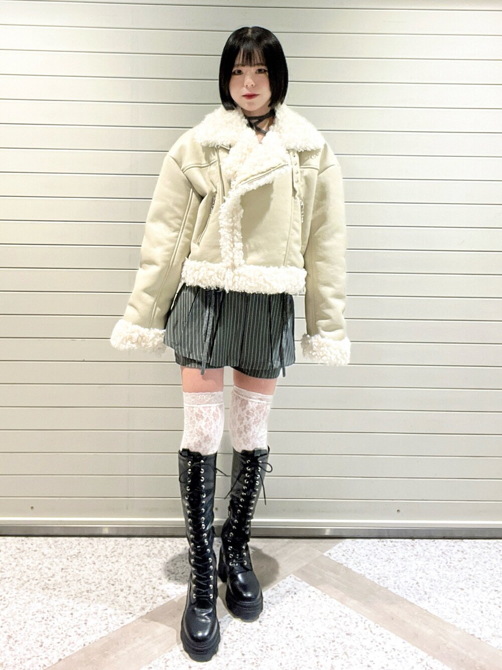 ホワイト系のムートンコート、グレー系のスカート、ブラック系のブーツを着用したレディースの冬コーディネートの2枚目の写真