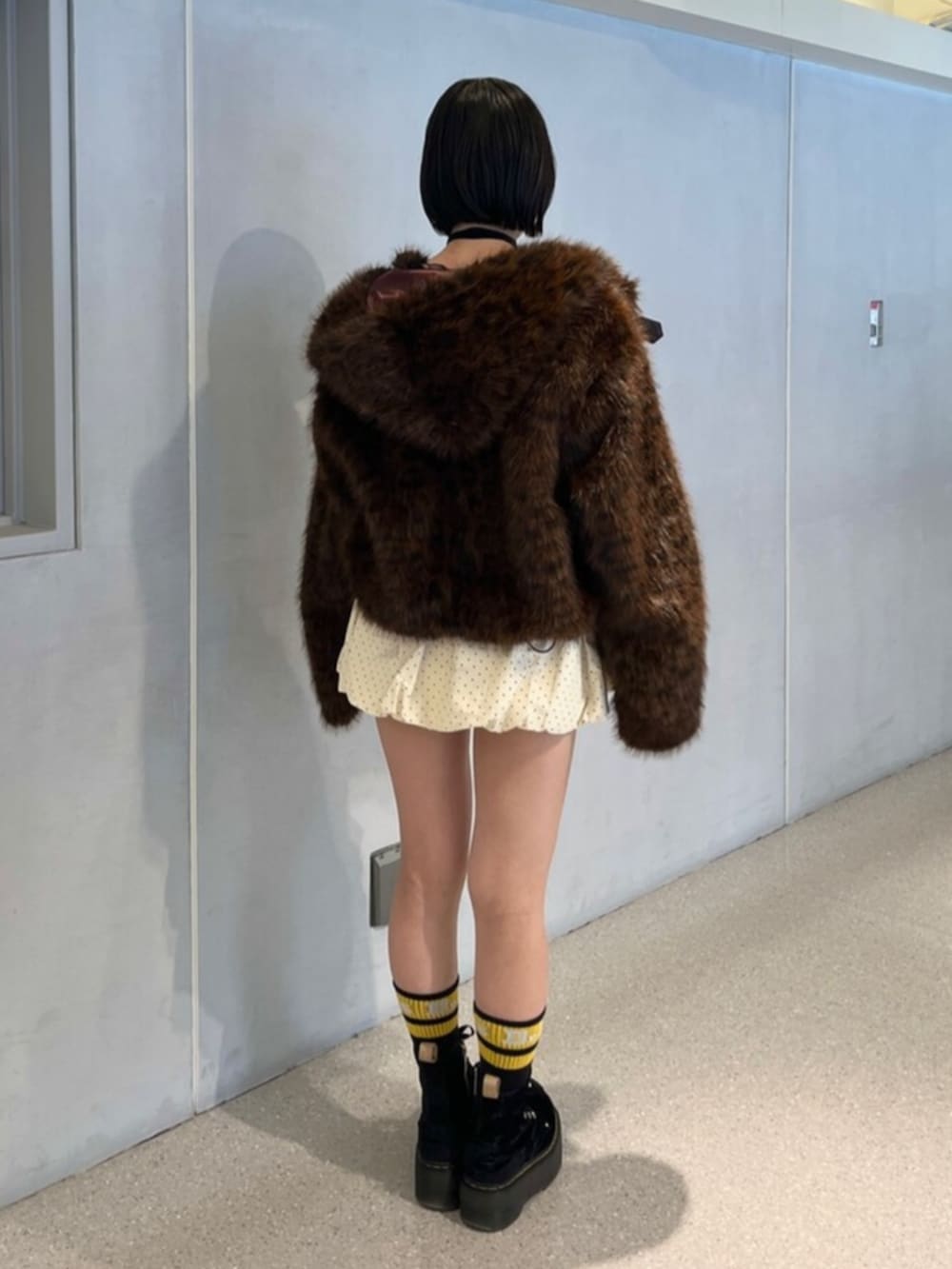 ホワイト系のスカート、ブラウン系のブルゾン、ブラック系のニット/セーターを着用したレディースの秋コーディネートの4枚目の写真