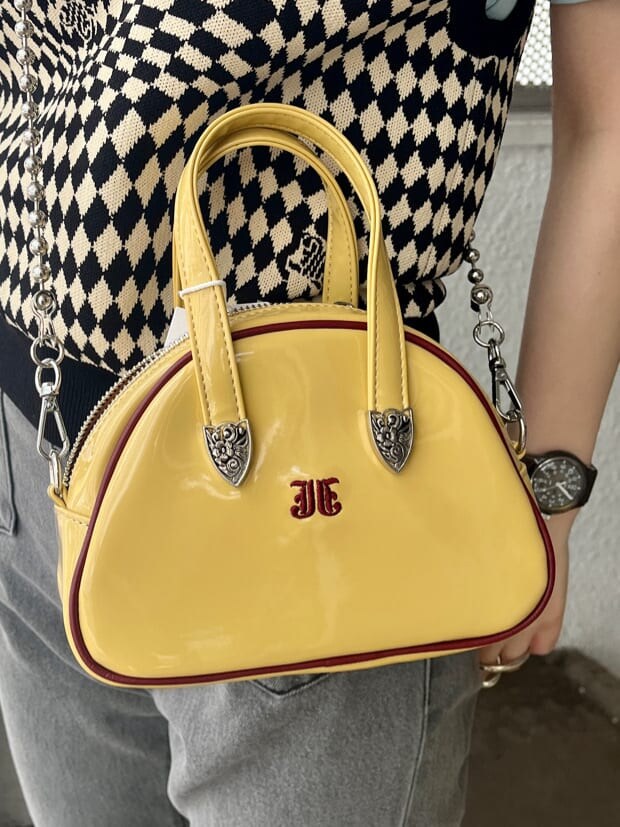 ブラック系のデニムパンツ、ブラック系のニット/セーター、イエロー系のボストンバッグを着用したレディースの夏コーディネートの9枚目の写真