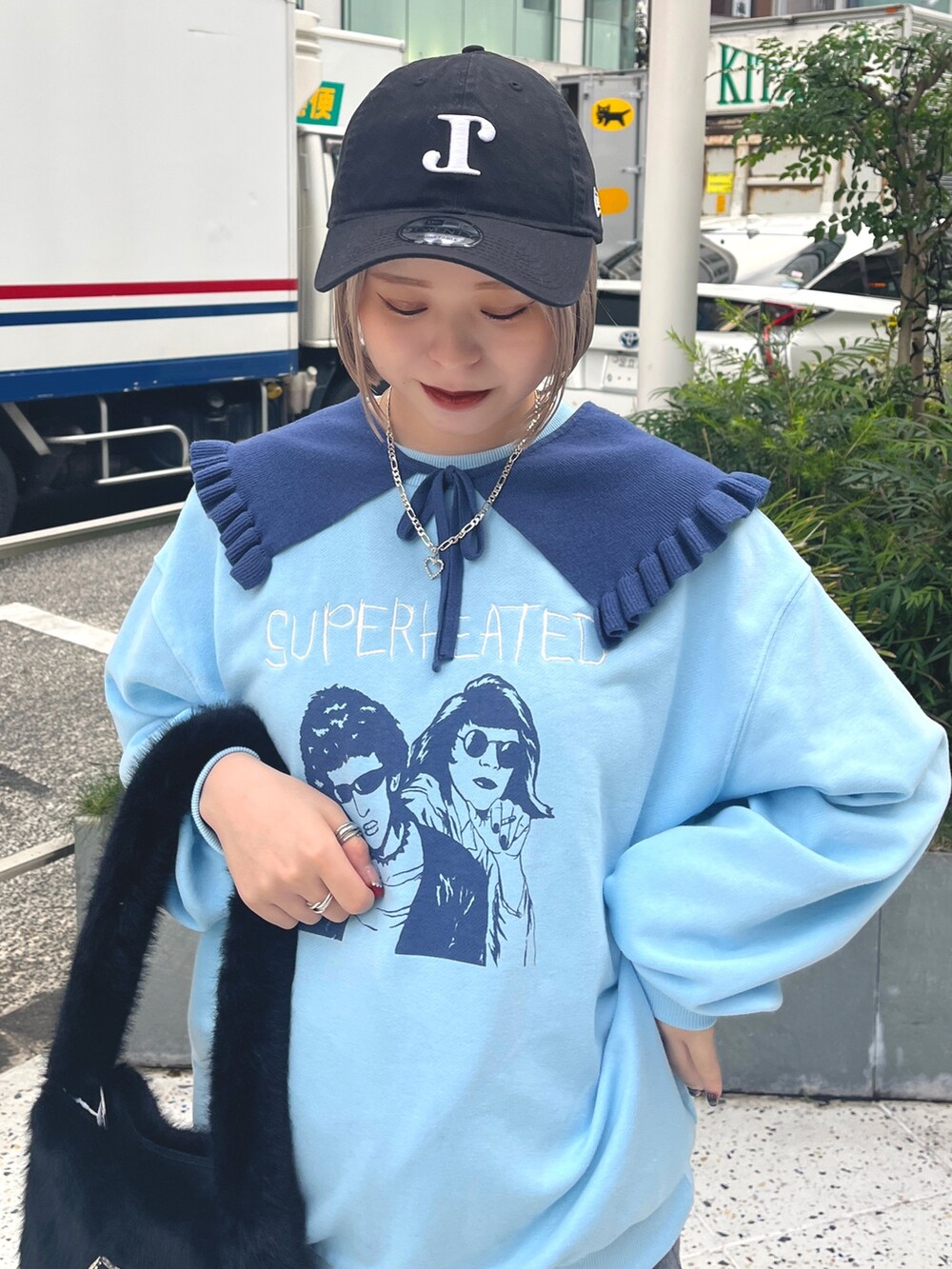 ブラック系のハンドバッグ、ブルー系のニット/セーター、グレー系のスカートを着用したレディースの冬コーディネートの5枚目の写真