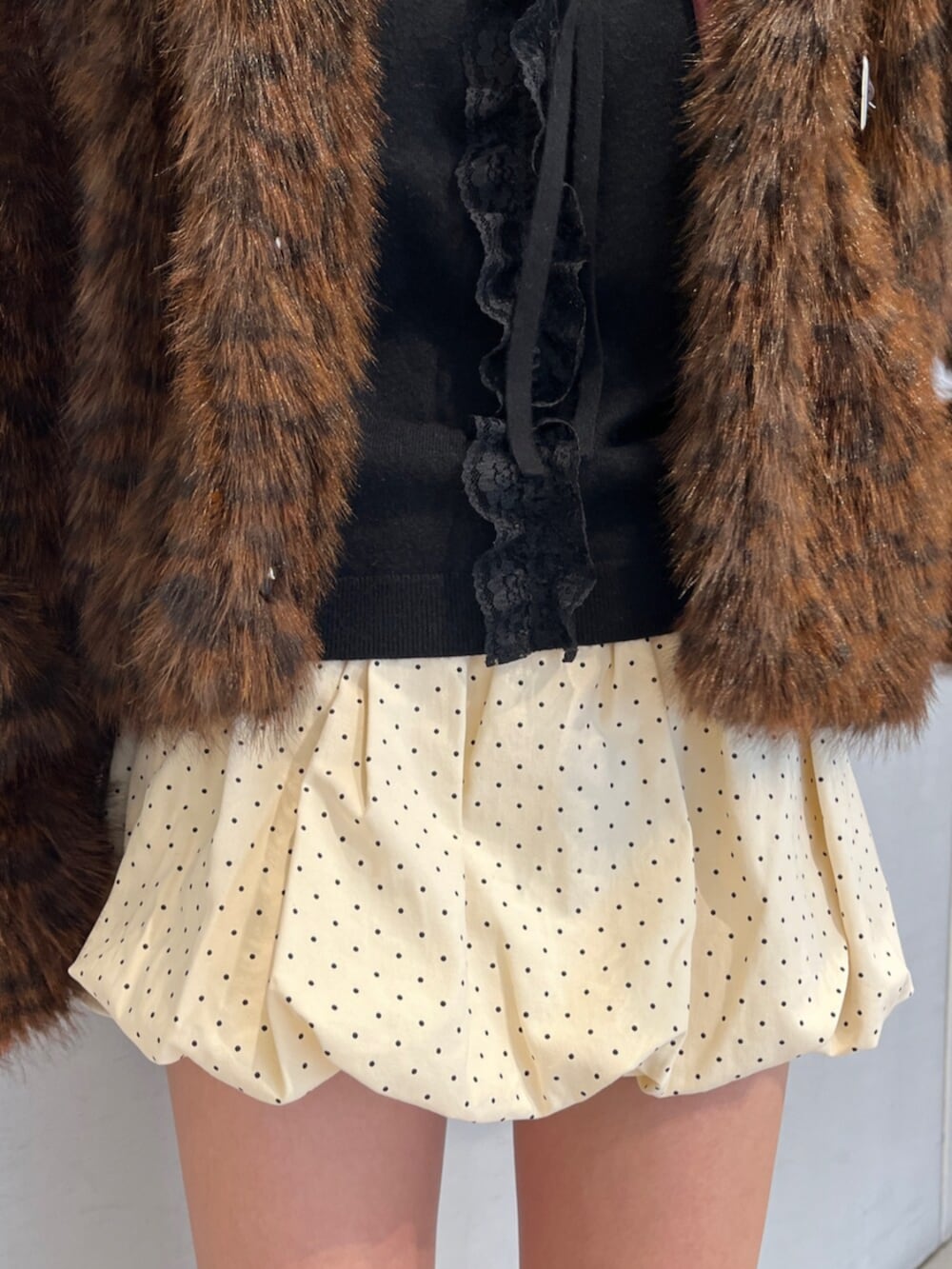 ホワイト系のスカート、ブラウン系のブルゾン、ブラック系のニット/セーターを着用したレディースの秋コーディネートの8枚目の写真