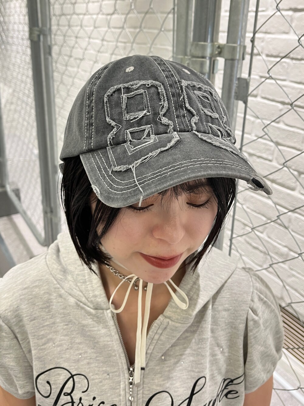 グレー系のワンピース、ブラック系のキャップ、ブラック系のチョーカーを着用したレディースの夏コーディネートの9枚目の写真