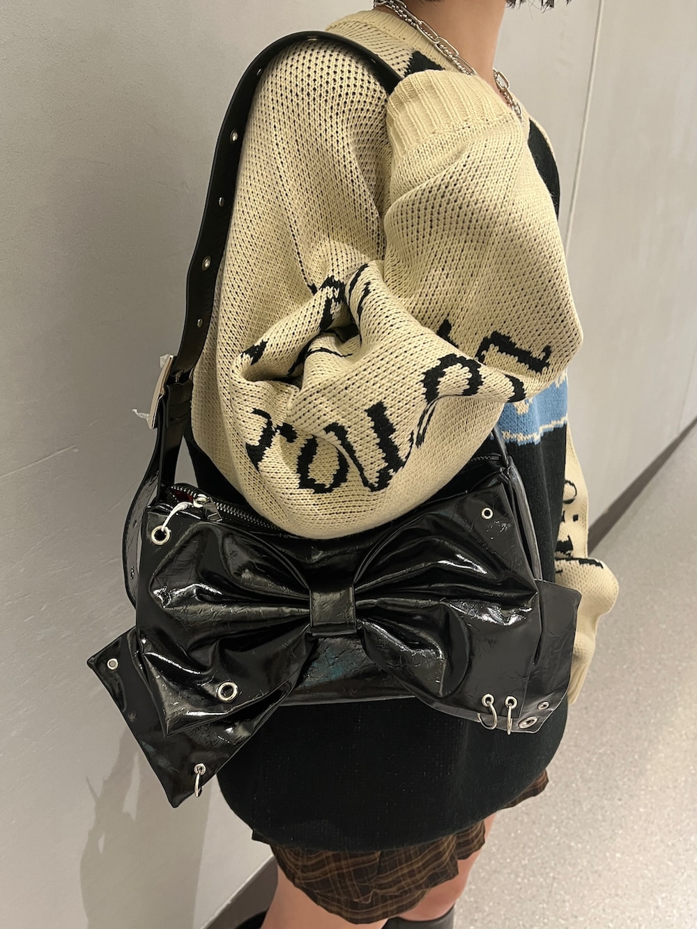 ブラック系のニット/セーター、ブラウン系のスカート、ブラック系のショルダーバッグを着用したレディースの秋コーディネートの9枚目の写真