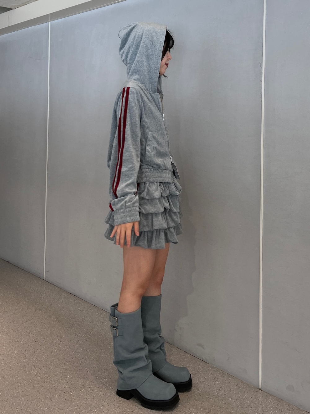 グレー系のパーカー、グレー系のスカート、ブルー系のブーツを着用したレディースの夏コーディネートの4枚目の写真