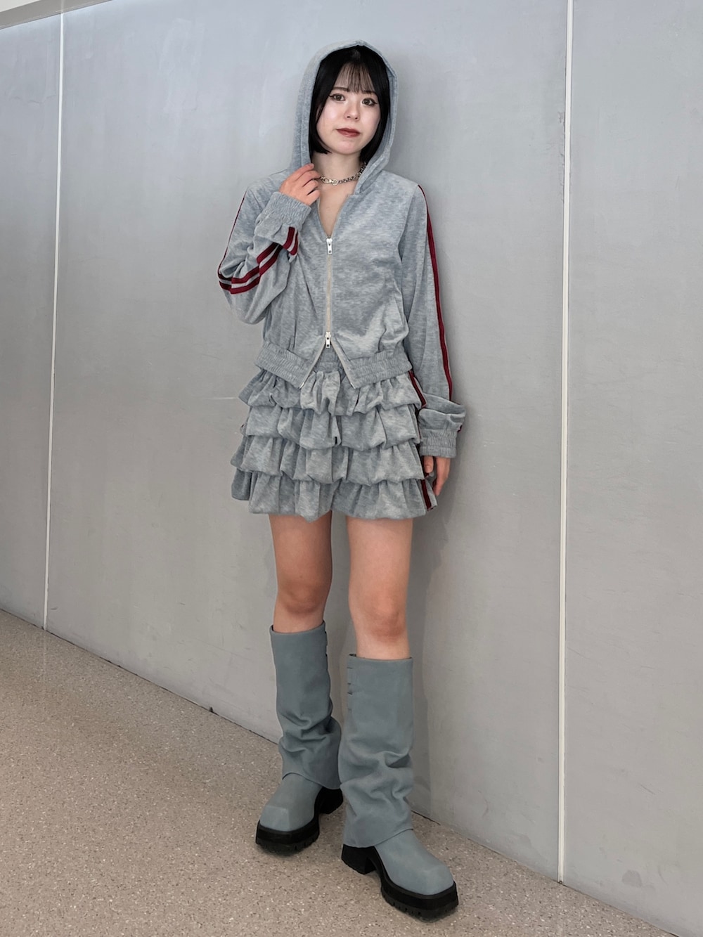 グレー系のパーカー、グレー系のスカート、ブルー系のブーツを着用したレディースの夏コーディネートの3枚目の写真