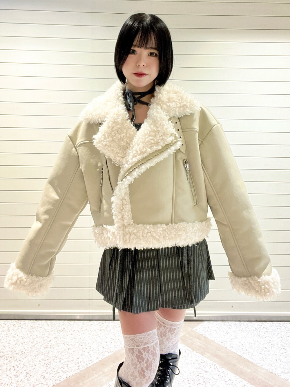 ホワイト系のムートンコート、グレー系のスカート、ブラック系のブーツを着用したレディースの冬コーディネートの5枚目の写真