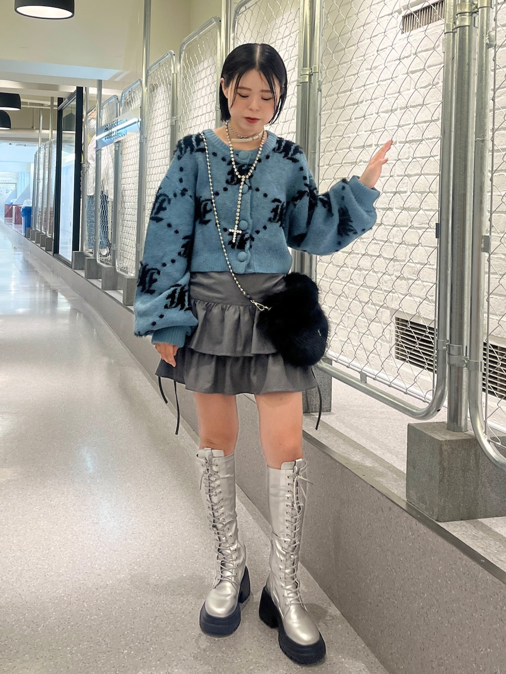 シルバー系のブーツ、ブルー系のカーディガン/ボレロ、ブラック系のハンドバッグを着用したレディースの夏コーディネートの2枚目の写真